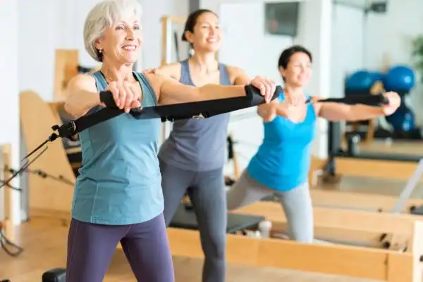 Toning Arms After 60: Empowering Womens Fitness Through Effective Weight Training 2 older woman doing weight training East Malling and resistance in the gym to tone upper arms