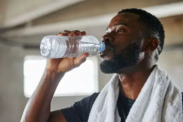 Hydration: The Secret Ingredient for a Toned Stomach and Enhanced Fitness 1 Image of man drinking water to improve hydration East Malling after work out.